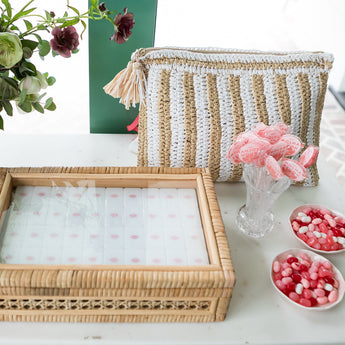 Handwoven rattan Mahjong tile box with glass top, neutral tones, and island-inspired details from the Island Collection. Fits a full-size tile set. With white Mahjong tile set from the House Collection, featuring intricately designed tiles with floral motifs, butterflies, and peacocks. Tile size: 1" x 1 7/16" x 7/16".