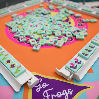Colorful TCU Mahjong mat with cowboy boots, gators, and “Go Frogs” pennants in bold purple, pink, orange, and blue
