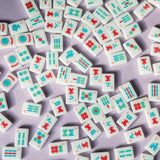 Classic white Mahjong tile set featuring colorful symbols in red, blue, and green arranged in suits and specialty tiles, displayed on a white background.