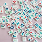 White Mahjong tile set from the House Collection, featuring intricately designed tiles with floral motifs, butterflies, and peacocks. Tile size: 1" x 1 7/16" x 7/16". 